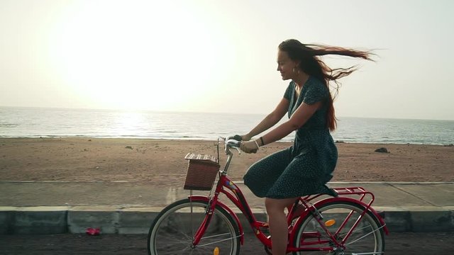 Redheaded woman riding vintage bicycle along coastline
