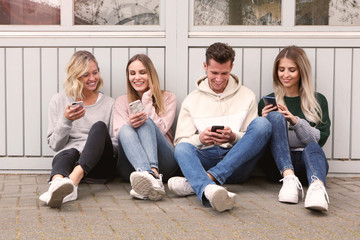 Junge Leute mit Handys sitzen auf dem Boden