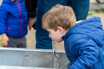 Fototapeta na wymiar Small child drinking water in a park