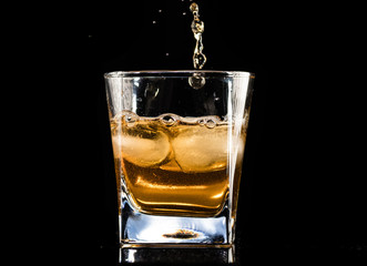 whiskey with ice in a steaming glass on a black background