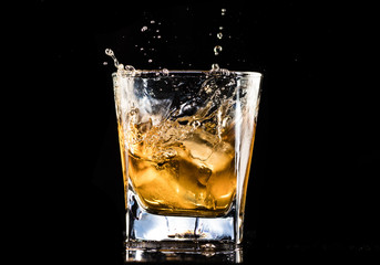 whiskey with ice in a steaming glass on a black background