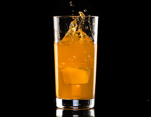 orange cocktail with mint syrup with ice in a glass on a black background