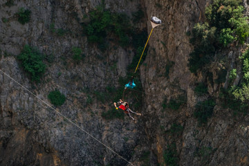 a man with a parachute jumping from a highline above the Red Lake, Split-Dalmatia, Imotski, Croatia