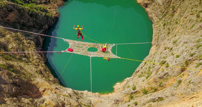 a man with a parachute jumping from a space net above the Red Lake, Split-Dalmatia, Imotski, Croatia