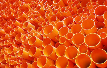 orange PVC pipes stacked in construction site