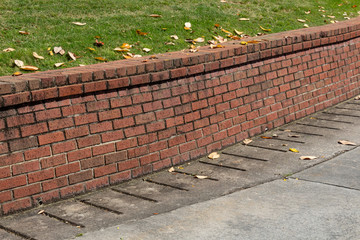 Brick retaining wall with green grass and concrete driveway, residential, horizontal aspect