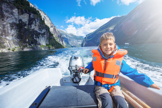 Portrait Of Young Boy Driving The Motorboat On The Geirangerfjord, Norway.