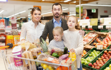 Obraz premium Family with daughters choosing meal for home in supermarket