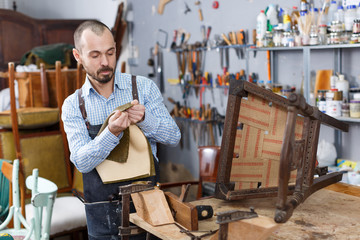 Craftsman reupholstering chair in workshop