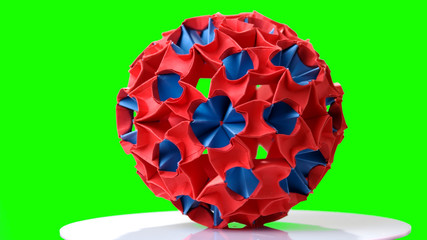 Origami figure on green background. Colorful kusudama model. Origami paper folding.