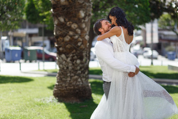 Beautiful wedding couple embracing in public park in Greece, looking at each other, in love. Love in air concept.