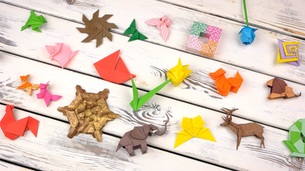 Set of origami objects on rustic wooden background. Collection of origami animals, flowers and abstract models on white wood. Childrens crafts contest.