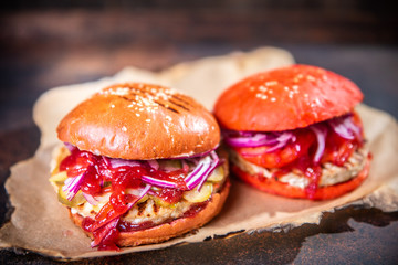 Fresh two homemade burgers on wooden board over dark wooden background.