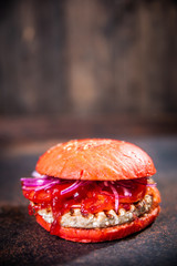 Fresh homemade burger on wooden board over dark wooden background.
