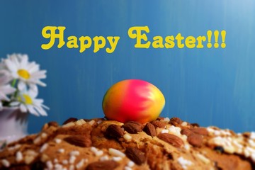 Easter egg on Easter pie and chamomiles on blue background with inscription Happy Easter!