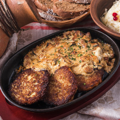 Potato pancakes with  sour cream sauce and mushrooms on a frying pan.