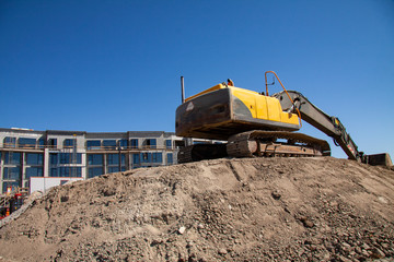 Excavator at building site under construction against the blue sky - Image with copy space