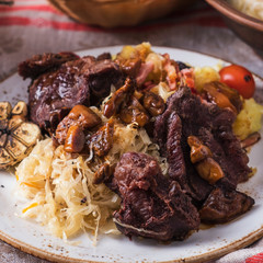 Beef cheeks with potato, sauerkraut and mushrooms. Closeup
