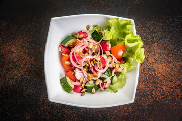 Fresh salad with mixed greens in bowl on wooden background.