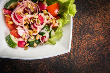 Fresh salad with mixed greens in bowl on wooden background.