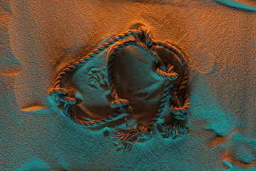 Naklejka premium top view of bend rope with knots on sand with orange and blue lights