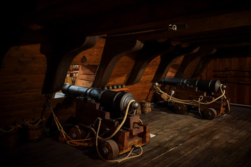 interior view of Cannons At The Deck and Cannon Balls plus windows on old galleon with ropes.