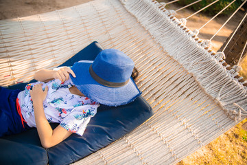 Fototapeta na wymiar Little girl with hat relaxing on hammock