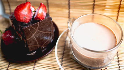 Ice cream cake makeup with strawberry sauce and fresh strawberries set with hot cocoa.