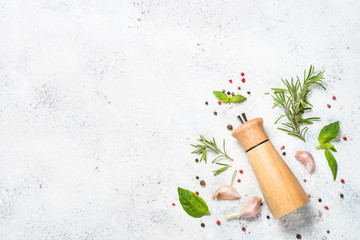 Pepper mill with fresh herbs on white. © nadianb