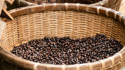 Dark roasted coffee beans In a bamboo weave basket.