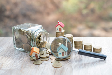 Miniature of house with magnifying glass and coin. house and money. toy house, magnifying glass and coins. concept of mortgage, construction, rental housing.