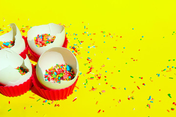 Multicolored Candy Sweets On Yellow Background. Closeup Of Multicolored Small Candies In The Eggshell. Minimal Art Design. Desserts, Holidays, Birthday Concept. Broken Eggs And Colorful Candies.