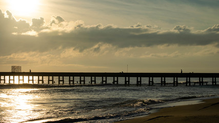 Silhouettes of fishermen fishing on  Bridge into the sea.