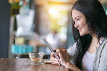 Beautiful woman in a coffee cafe uses a smartphone with relaxing