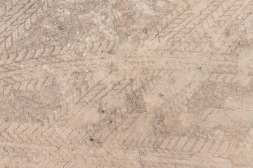 Fototapeta na wymiar Car wheel on a dirt road on the brown dry soil ground texture background.