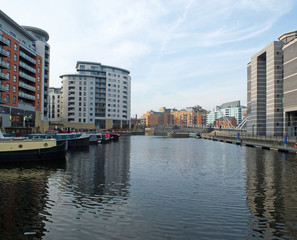 Fototapeta premium a view of clarence dock in leeds looking towards the lock and river with canal boats moored alongside apartment buildings and hotels reflected in the water