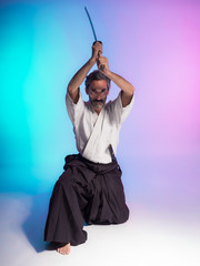 bearded man practicing aikido illuminated with colorful gels in studio photo with blue and pink background
