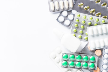 Pills in a blister and vitamins on white background flatlay.