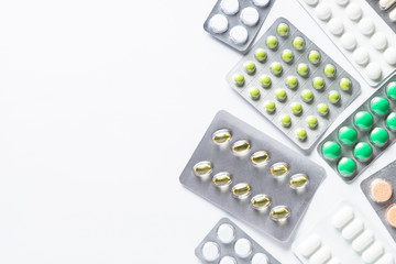 Pills in a blister and vitamins on white background flatlay.