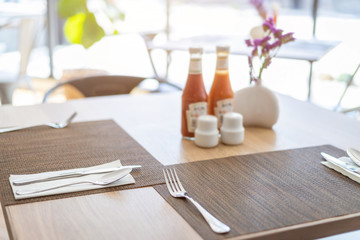 Close-up of luxurious spoon and fork, flower vaseson, sauce bottle the dining table decoration in hotel