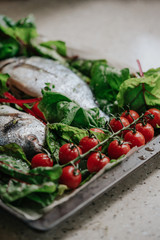 Fresh Dorado fish with tomatoes and herbs prepared for baking on a baking sheet