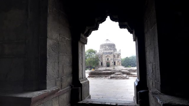 gimbal clip walking towards shish gumbad framed by an arch of bada gumbad at lodhi gardens in delhi, india