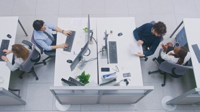 In Busy Office Rows of Young Professionals Working on Desktop Computers, Talking, Doing Client Support, Communicating with Customers, Monitoring Statistics, Walking Thorugh Hallway. High Angle Shot