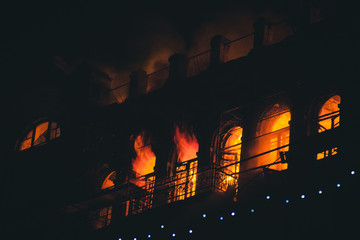 fire in the windows of the old building at night in winter against the background of garlands. fire...