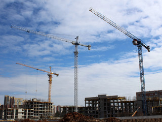 Construction site tower cranes against blue sky