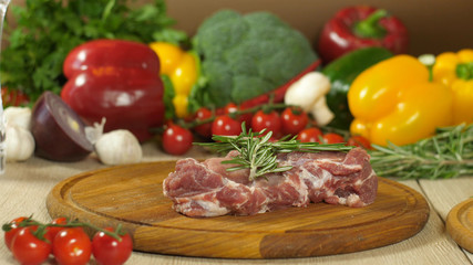 A large piece of raw meat on a background of vegetables.