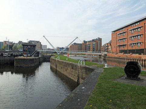 the leeds lock entrance to clarence dock with footbridge over the river aire and historic gates and mooring area surrounded by modern apartment developments