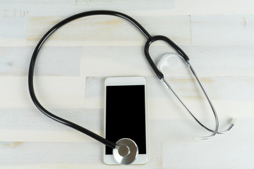 Fototapeta na wymiar A cellphone with a stethoscope on a wooden table