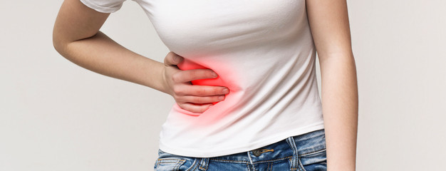 Woman in pain holding her stomach on right side