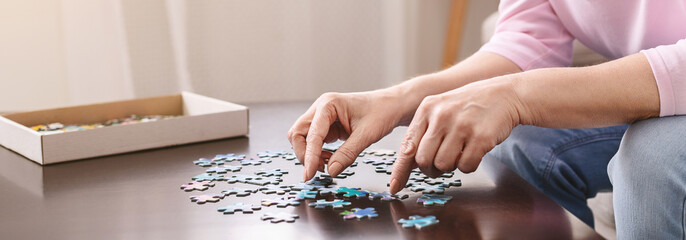 Hands of senior woman playing puzzle as dementia prevention - obrazy, fototapety, plakaty